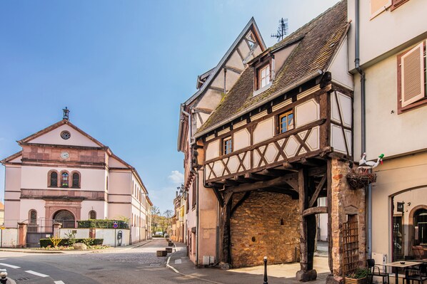 A street with traditional half-timbered houses, a church, and a stone bridge.