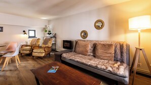 A living room with a sofa, chairs, a coffee table, and a fireplace.