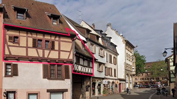 A street with traditional European architecture, including half-timbered houses and a cobblestone road.