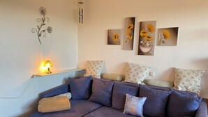 A living room with a sectional sofa, a small table, and wall art. - Complete Apartment With own Balcony (Vohenstrauss)