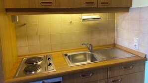 A kitchen with wooden cabinets, a stainless steel sink, and a gas stove. - Complete Apartment With own Balcony (Vohenstrauss)