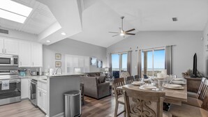 Una cocina amplia con electrodomésticos modernos, un comedor con una mesa grande y vistas al océano a través de amplios ventanales.
