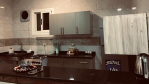 A modern kitchen with a gas stove, black countertop, and light blue cabinets.