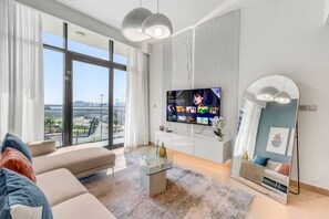 En moderne stue med stort TV, sofa, sofabord og et stort spejl.