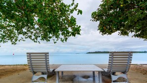 Two metal benches with a table in between, overlooking a calm body of water with a distant shoreline. - Sheridan by the Seashore (BONGAREE)