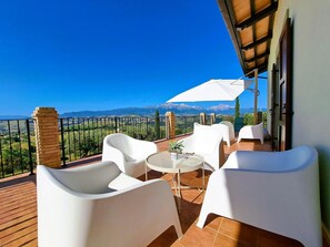 Ein Balkon mit weißen Stühlen, einem runden Tisch und einem Blumentopf.