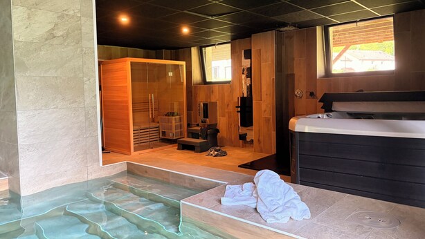 Ein Spa-Raum mit Glasboden, Holzvertäfelung, einer Sauna und einem Whirlpool.