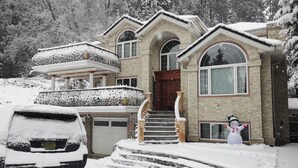 Una casa a due piani con un tetto imbiancato dalla neve e delle scale.