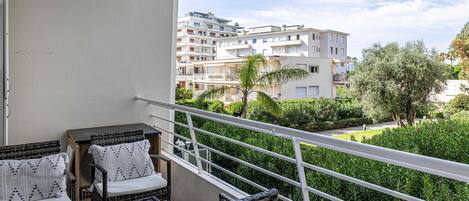 A balcony with wicker furniture and a view of residential buildings and greenery.