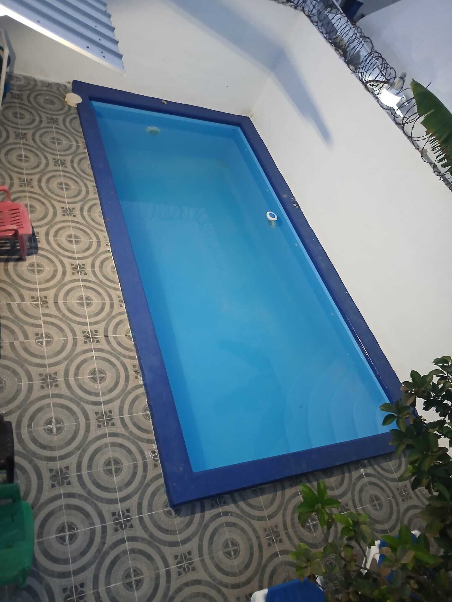 A rectangular pool with a blue interior and a white exterior, surrounded by patterned tiles.