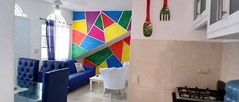 A modern kitchen with a gas stove, a water dispenser, and a colorful geometric wall art.