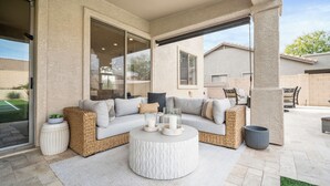 A covered patio area with a sectional sofa, a round coffee table, and a glass enclosure. - Scottsdale Getaway- Luxury Home, 5-Star Location, Golf, Shop, Hike, Restaurants (Scottsdale)