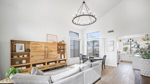 A modern living room with a wooden cabinet, a grey sofa, and a dining area with a table and chairs. - Scottsdale Getaway- Luxury Home, 5-Star Location, Golf, Shop, Hike, Restaurants (Scottsdale)