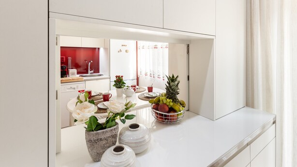 A modern kitchen with white cabinets, a white countertop, and a fruit bowl with various fruits. There are three white vases on the countertop. - D&S - Torne Apartments II (Vila Nova de Gaia)