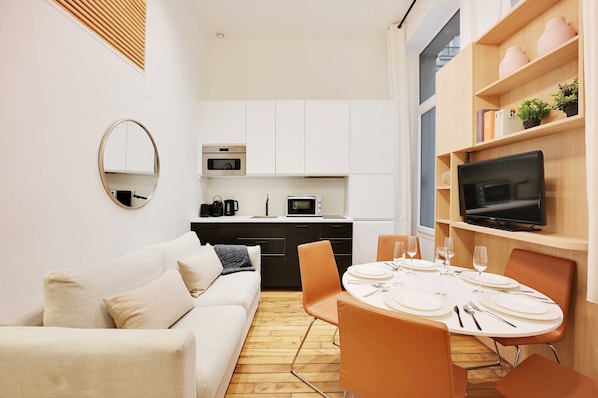 A compact living space with a kitchenette, a dining area, and a sofa.