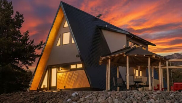 A modern house with a triangular roof, large windows, and a covered outdoor seating area. - A-Frame, HotTub, FirePit, Pergola, UFO Playscape, MiniAFrame ADU (Crestone)