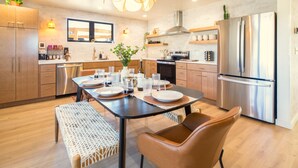 A modern kitchen with a dining area, featuring a central island, stainless steel appliances, and wooden cabinetry. - A-Frame, HotTub, FirePit, Pergola, UFO Playscape, MiniAFrame ADU (Crestone)