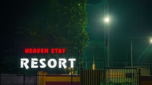 Ein bewachtes Eingangstor zu einem Resort, mit dem Schild "HEAVEN STAY RESORT".
