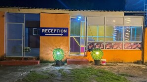 Ein Gebäude mit Empfangsbereich, Glastüren und einem Schild, das den Weg zur Rezeption weist.