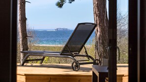 A wooden deck with a metal-framed lounge chair facing a body of water. - Gorgeous home in Knebel with sauna (Knebel)
