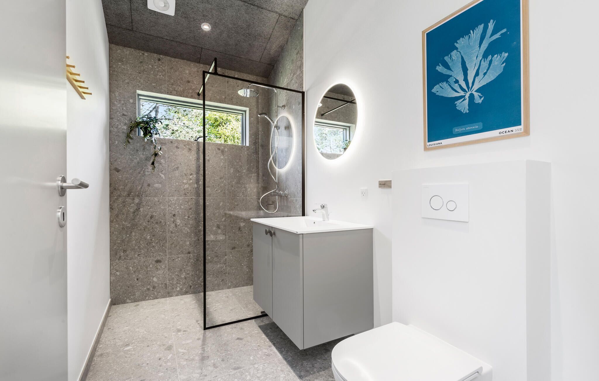 A modern bathroom with a glass-enclosed shower, a white sink, and a toilet.