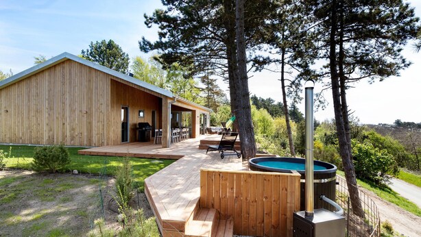 A wooden cabin with a deck, outdoor seating, and a hot tub. - Gorgeous home in Knebel with sauna (Knebel)