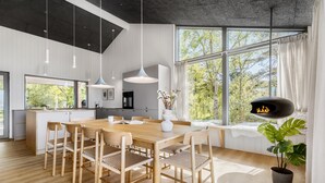 A modern kitchen with a large island, wooden chairs, pendant lights, and a black fireplace. - Gorgeous home in Knebel with sauna (Knebel)