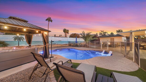 A swimming pool with a view of the beach, outdoor seating, and a covered area with string lights. - Unique 4-bed, 3-bath house with Pool, Hot Tub, Arcade and Hi-Spd Wifi (Tempe)