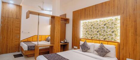 A hotel room with a large bed, a smaller bed, a wardrobe, a bedside table, a nightstand, and a wall-mounted light fixture.