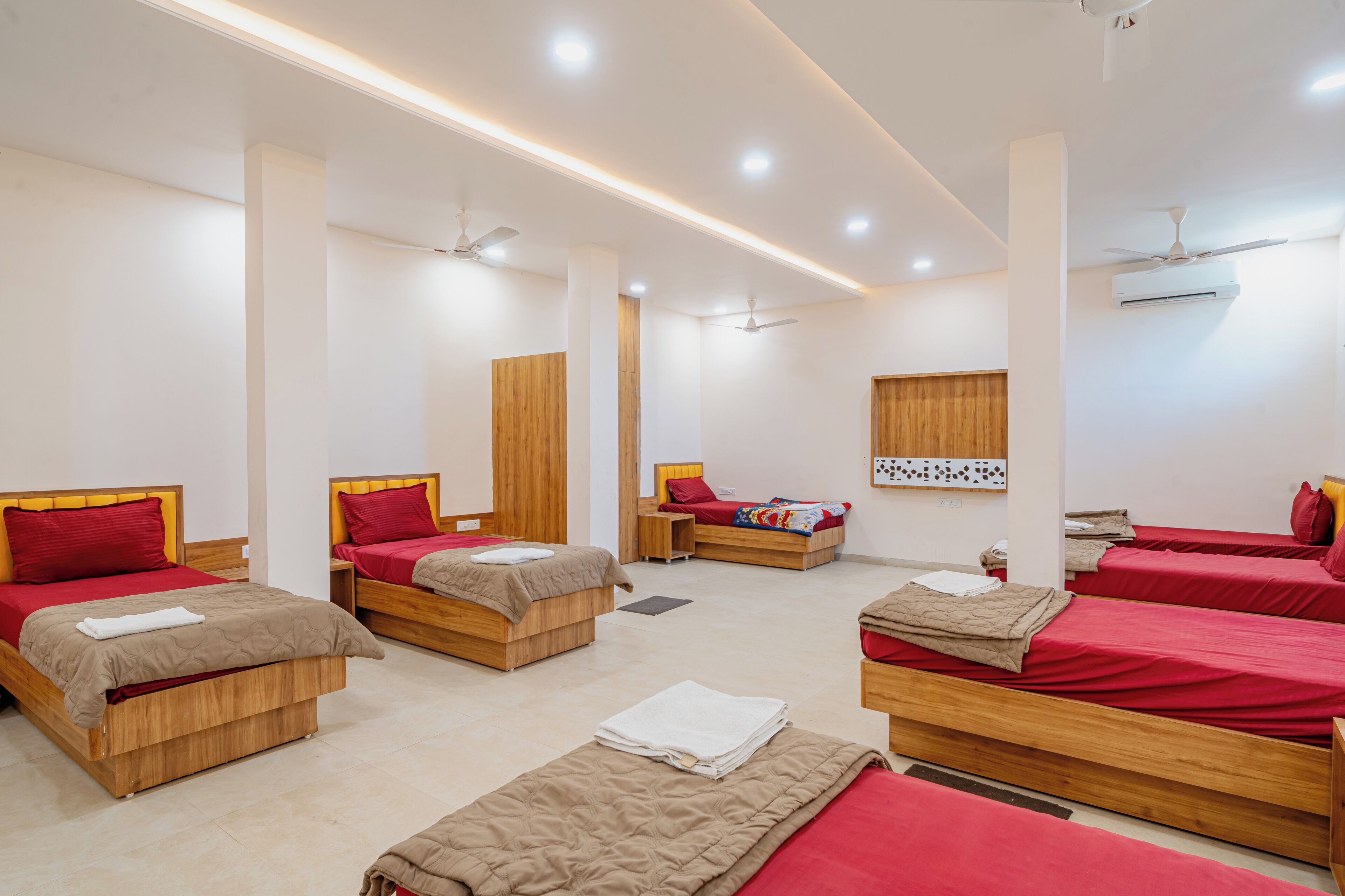 A hotel room with multiple beds, wooden headboards, and ceiling fans.