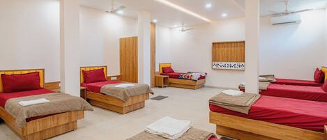 A hotel room with multiple beds, wooden headboards, and ceiling fans.