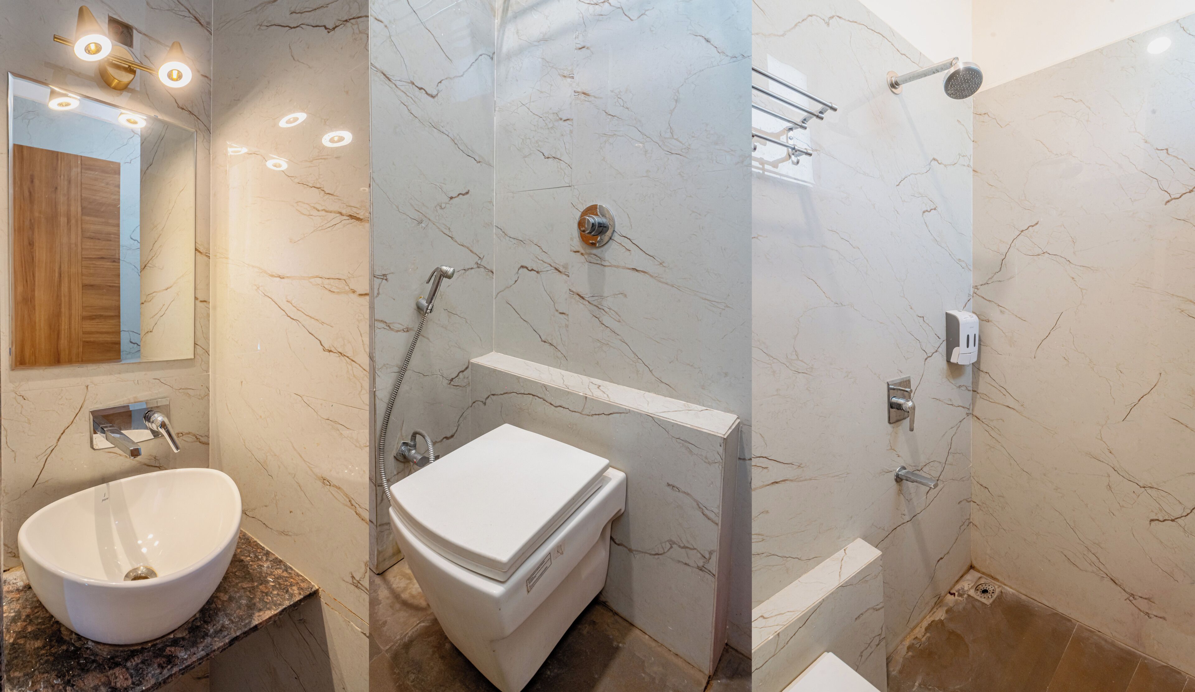 A bathroom with a marble vanity, a toilet, a shower with a glass door, and a mirror with lights.