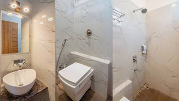 A bathroom with a marble vanity, a toilet, a shower with a glass door, and a mirror with lights.