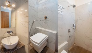 A bathroom with a marble vanity, a toilet, a shower with a glass door, and a mirror with lights. - Hotel Vatika Inn (Sohagpur)