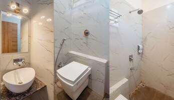A bathroom with a marble vanity, a toilet, a shower with a glass door, and a mirror with lights.