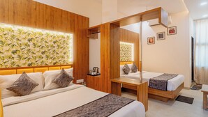 Una habitación de hotel con dos camas, cabeceros de madera, un ventanal con cortinas y una pared con un diseño de papel tapiz tropical.
