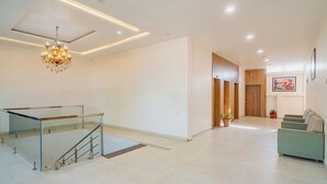 Un interior espacioso con una escalera, una araña, un sofá verde y una puerta de madera.