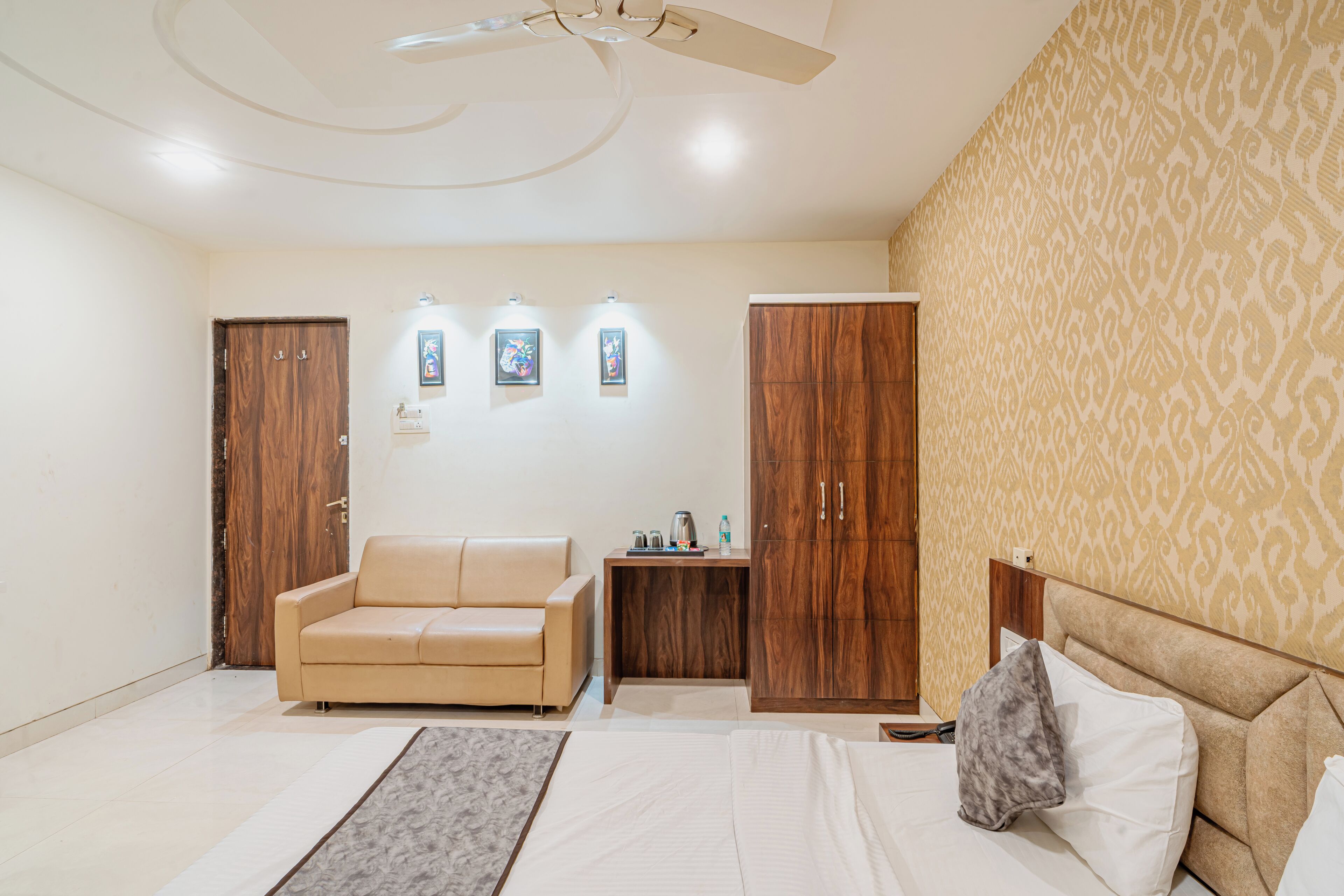 A bedroom with a bed, a sofa, a wardrobe, a nightstand, and a ceiling fan.