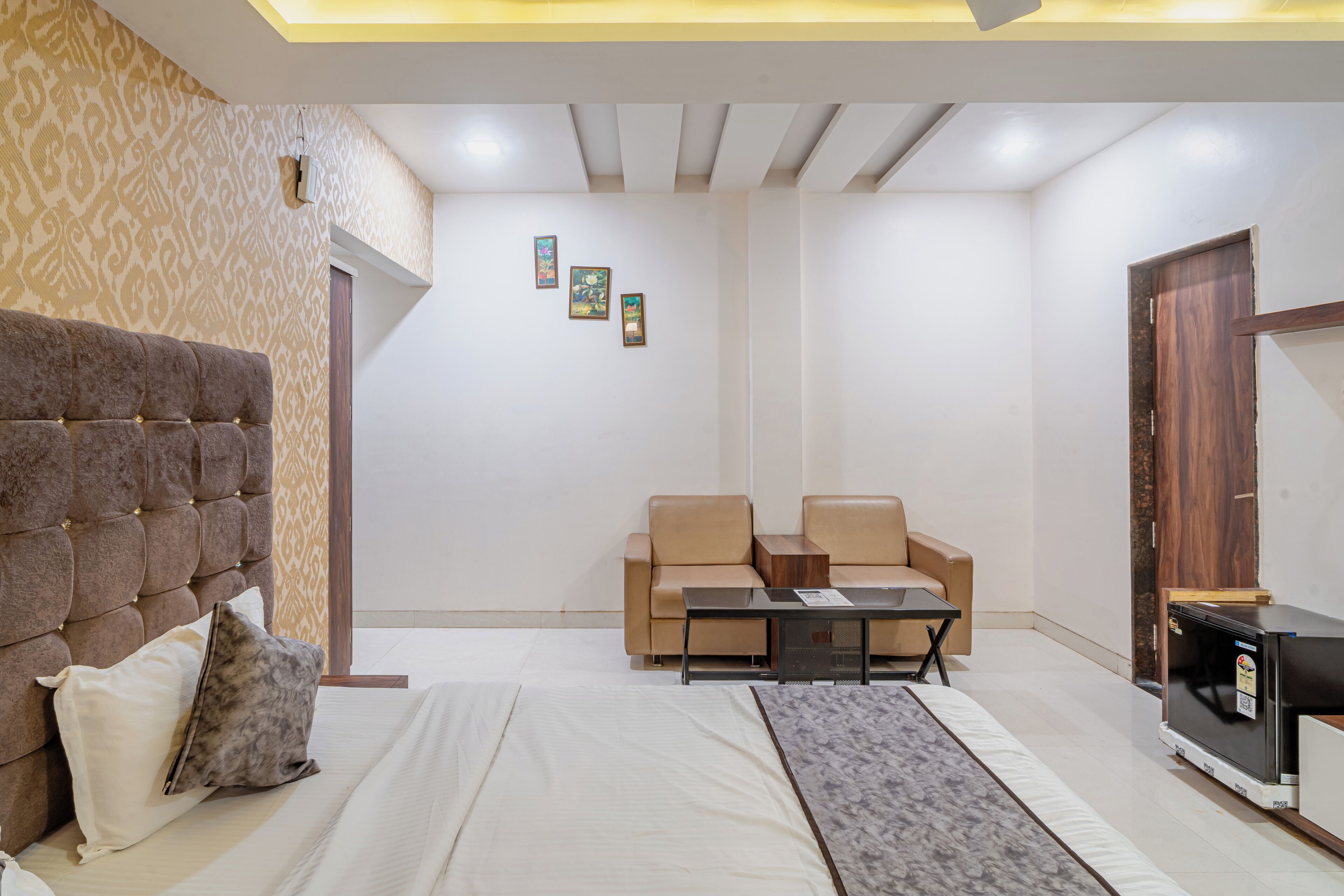 Un dormitorio moderno con cabecera capitonada, una cama, un sofá, una mesita de centro y un mueble para televisor.