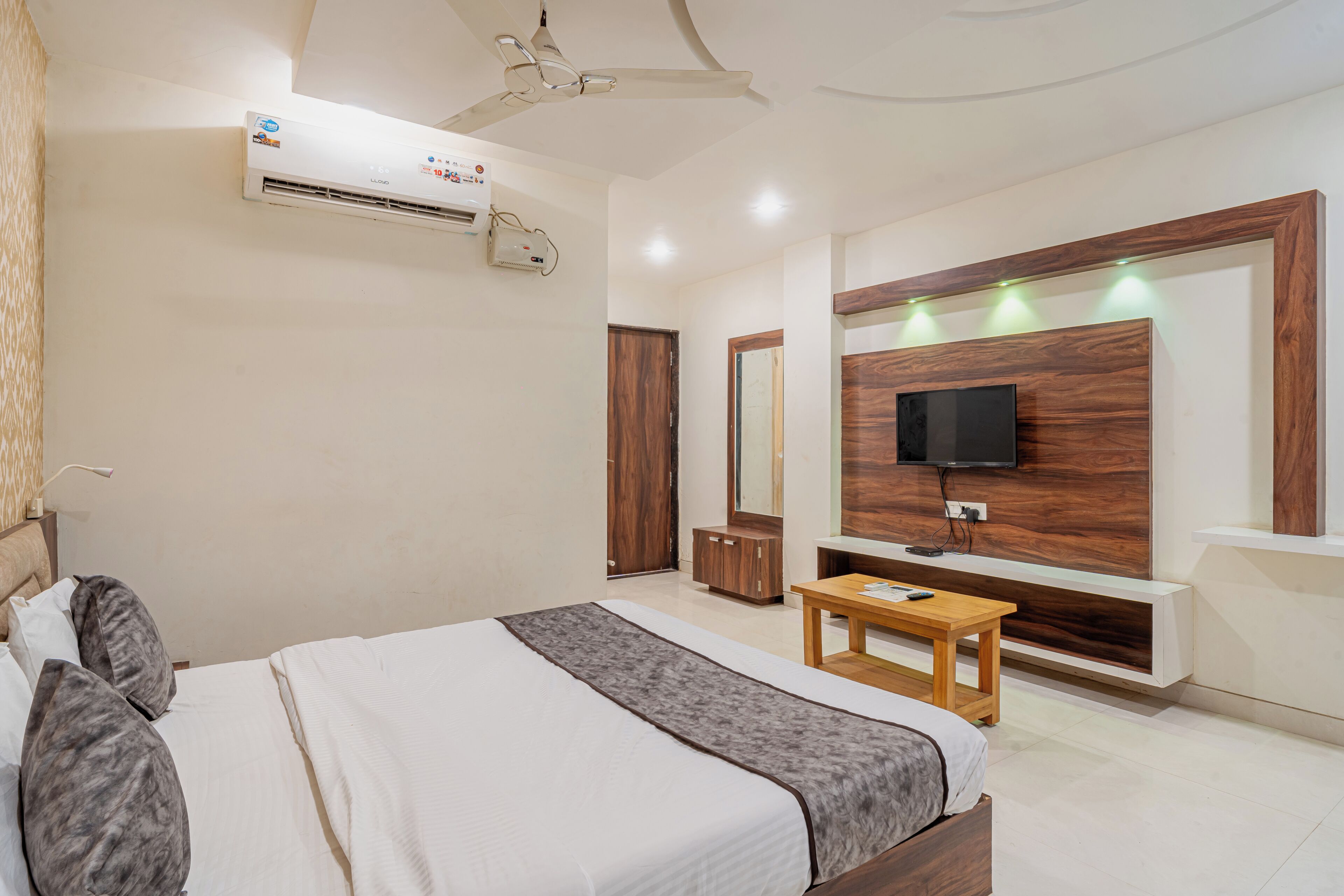 Une chambre d’hôtel équipée d’un lit, d’une table de chevet, d’une télévision, d’une armoire et d’un appareil de climatisation.