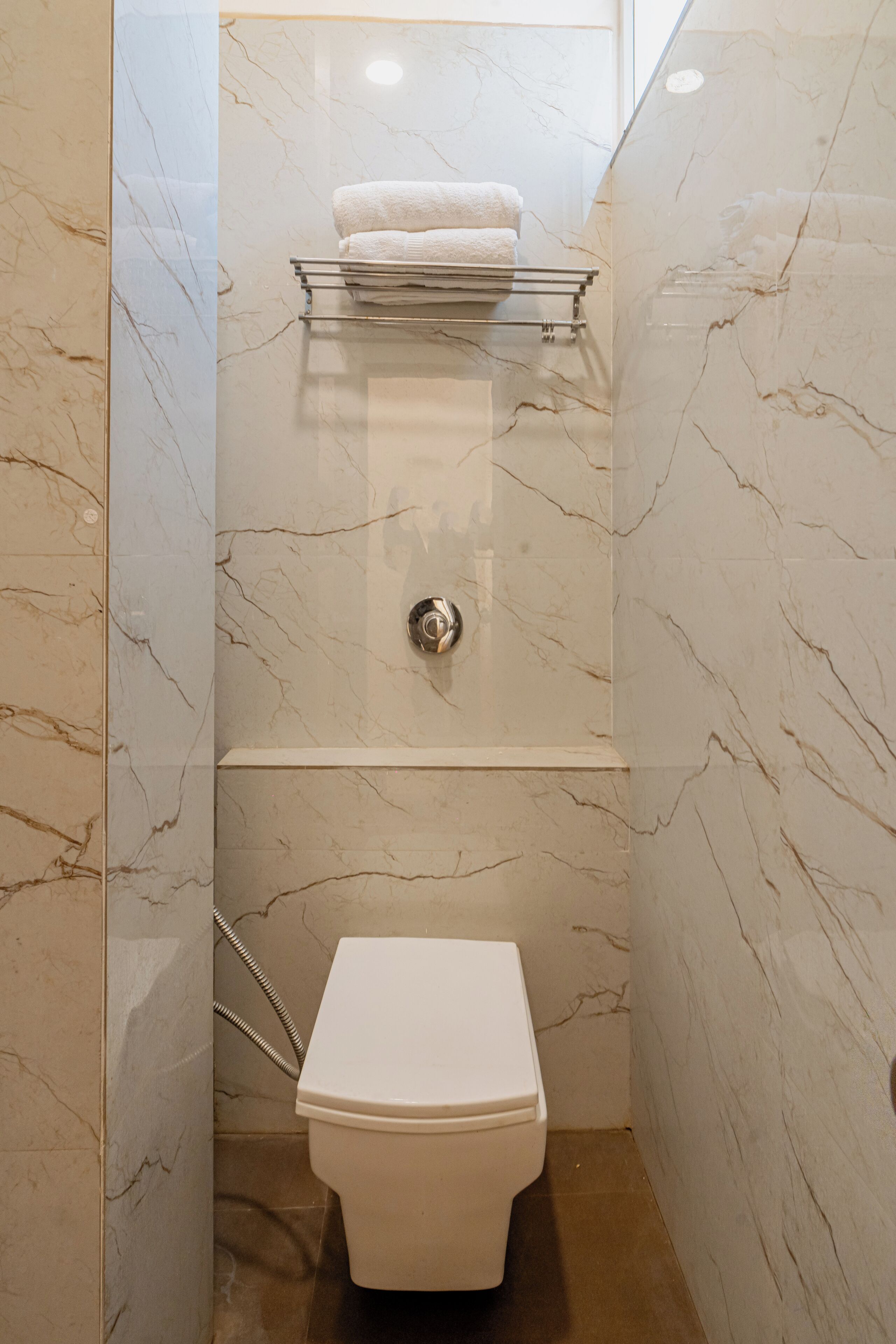 Une salle de bain équipée de toilettes, d’un porte-serviettes et d’une pomme de douche.