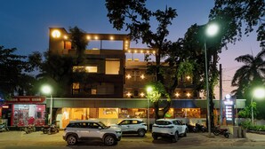 Un edificio de varios pisos con un restaurante en la planta baja y varios coches aparcados.