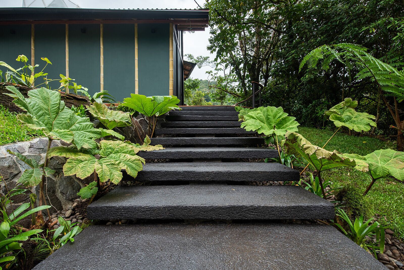 A set of stone steps leading to a traditional building with a green exterior.