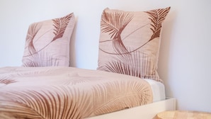 A bed with a leaf-patterned bedspread and two pillows with a similar design.