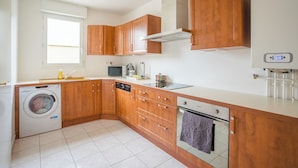 A compact kitchen with wooden cabinets, a built-in washing machine, a microwave, and a stove.