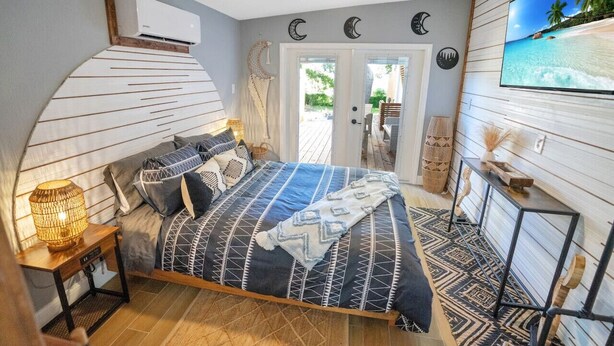 A bedroom with a bed, bedside lamp, and a TV on the wall. - Peaceful Lake View Retreat Near Parks 10 Minutes to Downtown (Orlando)