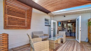 An outdoor patio with wicker furniture, a glass table, and a wooden deck. - Peaceful Lake View Retreat Near Parks 10 Minutes to Downtown (Orlando)