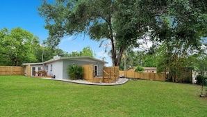 A single-story house with a front porch, a small deck, and a fenced backyard. - Lake view + 10min to dwtn + near parks + 2 guests! (Orlando)