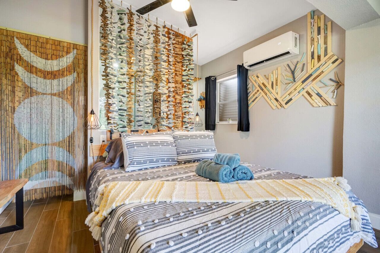 Una camera da letto con un letto, un'opera d'arte a parete e una ventola a soffitto.