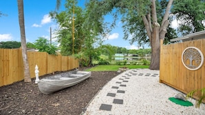 A backyard with a boat, a wooden fence, and a circular wooden structure with a tree design. - Lake view + 10min to dwtn + near parks + 2 guests! (Orlando)